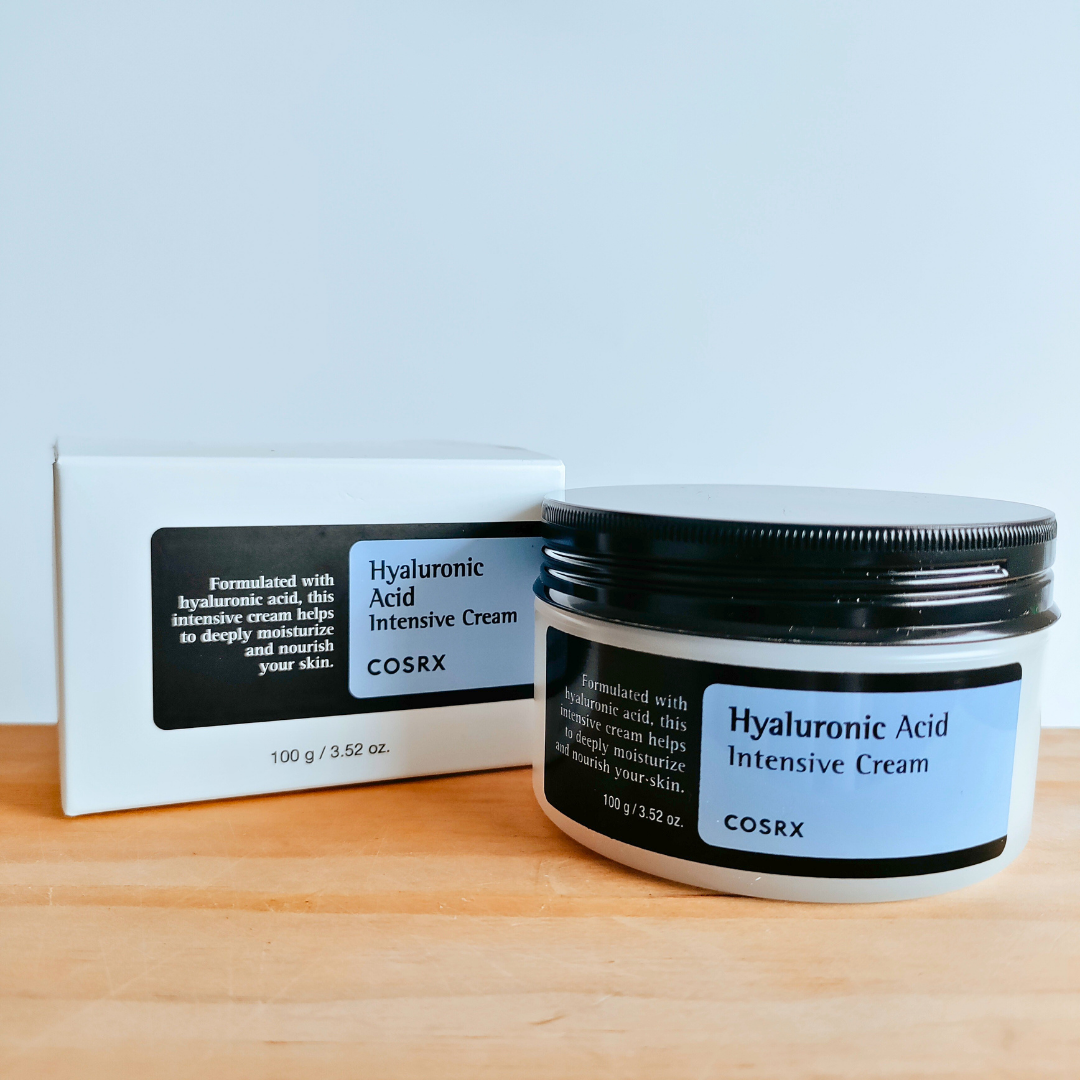 COSRX Hyaluronic Acid Intensive Cream jar and box on a wooden surface with a light blue background