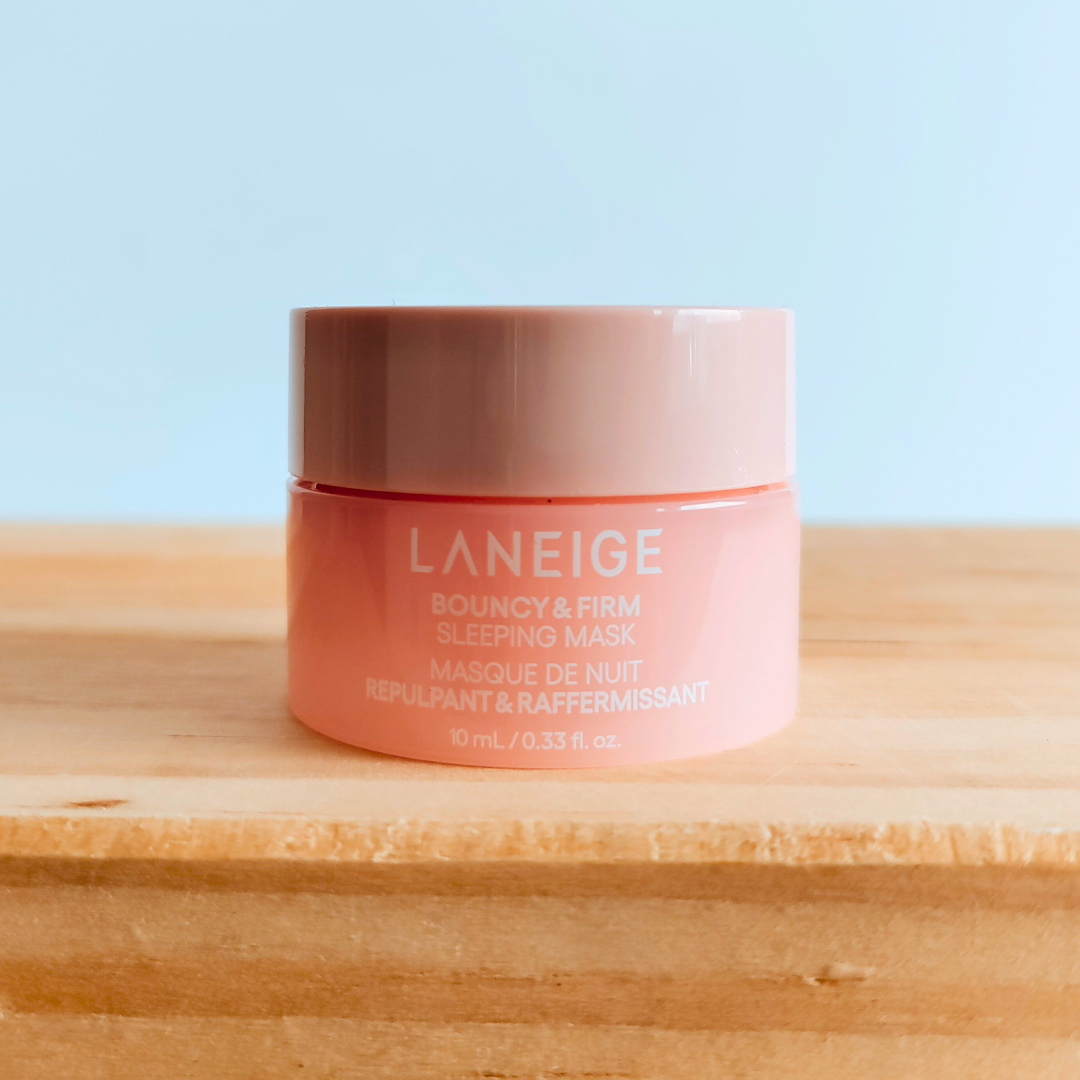 Laneige bouncy & firm sleeping mask jar on a wooden surface with a light blue background