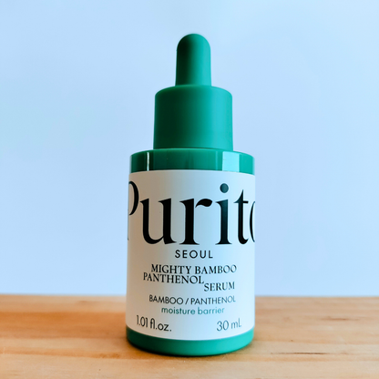 Purito serum bottle on a wooden surface with a light blue background