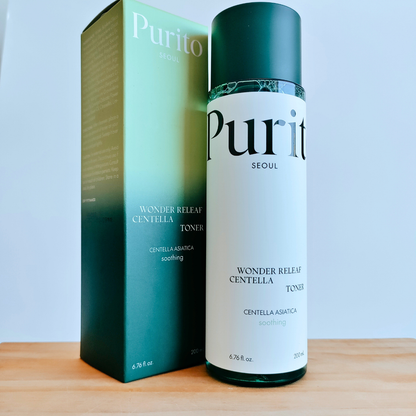 Purito toner bottle and packaging on a wooden surface with a light blue background